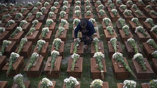 A woman places flowers on coffins holding the partial remains of 172 unidentified people. For the anonymous bones interred in San Juan Comalapa on the National Day Against Forced Disappearance, a genetic database holds their information in case relatives can be located in the future. (Rodrigo Abd / AP) A woman places flowers on coffins holding the partial remains of 172 unidentified people. For the anonymous bones interred in San Juan Comalapa on the National Day Against Forced Disappearance, a genetic database holds their information in case relatives can be located in the future. (Rodrigo Abd / AP)