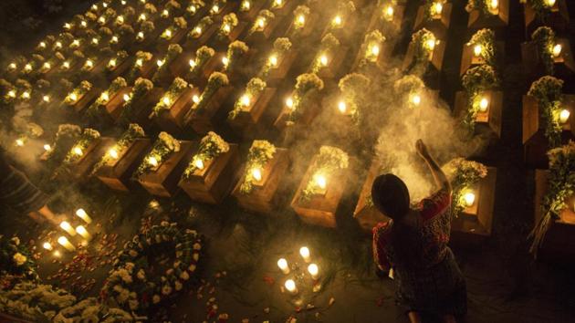 A woman spreads incense over coffins holding the remains of 172 unidentified people who were discovered buried at what once was a military camp in San Juan Comalapa, Guatemala, one day before their formal burial at the same site where they were discovered. (Rodrigo Abd / AP) A woman spreads incense over coffins holding the remains of 172 unidentified people who were discovered buried at what once was a military camp in San Juan Comalapa, Guatemala, one day before their formal burial at the same site where they were discovered. (Rodrigo Abd / AP)