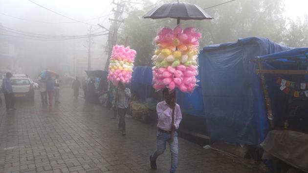 Travelling vendors selling cotton-candy walk amid fog in Dharmsala on July 9, 2018. (Ashwini Bhatia / AP) Travelling vendors selling cotton-candy walk amid fog in Dharmsala on July 9, 2018. (Ashwini Bhatia / AP)