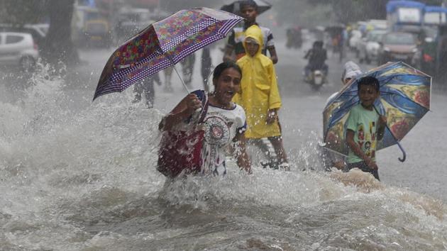 A woman walking through a water logged street, reacts as a truck driving past leaves ripples during monsoon rains in Mumbai on July 8, 2018. (Rafiq Maqbool / AP) A woman walking through a water logged street, reacts as a truck driving past leaves ripples during monsoon rains in Mumbai on July 8, 2018. (Rafiq Maqbool / AP)