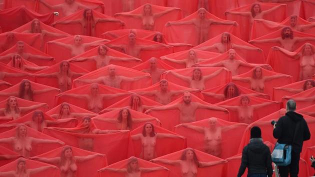 Over 200 people pose partially naked on a shopping centre rooftop car park as part of the latest project by US photographer Spencer Tunick (R) in Melbourne, Australia. The photo shoot had an apocalyptic theme, with participants draped in translucent red capes. (Paul Crock / AFP) Over 200 people pose partially naked on a shopping centre rooftop car park as part of the latest project by US photographer Spencer Tunick (R) in Melbourne, Australia. The photo shoot had an apocalyptic theme, with participants draped in translucent red capes. (Paul Crock / AFP)