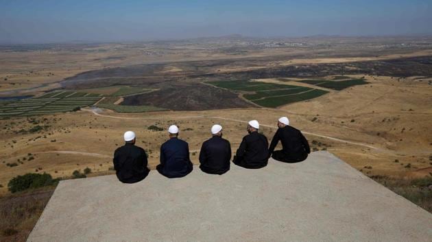 Druze men at the Israeli-annexed Golan Heights look out across the southwestern Syrian province of Quneitra, visible across the border. (Jalaa Marey / AFP) Druze men at the Israeli-annexed Golan Heights look out across the southwestern Syrian province of Quneitra, visible across the border. (Jalaa Marey / AFP)