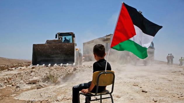 A Palestinian boy sits on a chair with a national flag as Israeli authorities demolish a school site in the village of Yatta, south of the West Bank city of Hebron and to be relocated in another area. (Hazem Bader / AFP) A Palestinian boy sits on a chair with a national flag as Israeli authorities demolish a school site in the village of Yatta, south of the West Bank city of Hebron and to be relocated in another area. (Hazem Bader / AFP)
