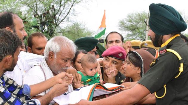 An army officer gives the national flag wrapped on the body of martyr Mukit Bihari Meena of Jhalawar to his son on Sunday.(HT Photo)
