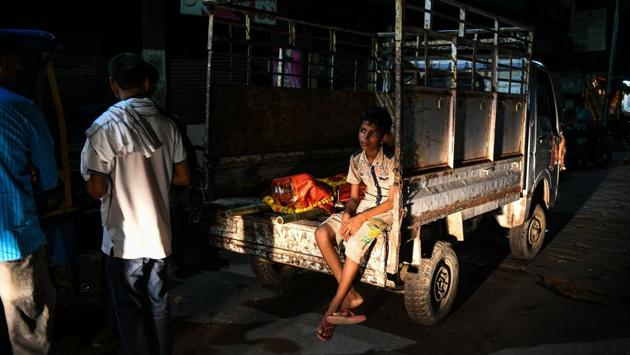 A boy sits on a van with the dead body of a relative. Choudhary wanted his two sons to find a different path in life, but both dropped out of school to follow in their father’s footsteps, he said. They will become the fifth generation from his family to tend the pyres. (Chandan Khanna / AFP) A boy sits on a van with the dead body of a relative. Choudhary wanted his two sons to find a different path in life, but both dropped out of school to follow in their father’s footsteps, he said. They will become the fifth generation from his family to tend the pyres. (Chandan Khanna / AFP)