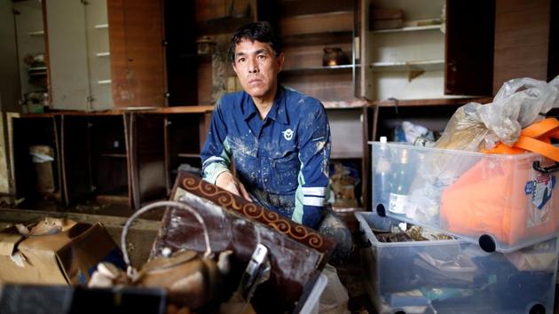 Kairyu Takahashi removes debris from his house. Competition for a dwindling budget was partly behind the delay, as was an environmental impact study, said Takahashi, head of the prefectural legislature, and a member of a committee that discusses regional public works projects. “I feel powerless that I wasn’t able to make the government take action,” he said. (Issei Kato / REUTERS) 