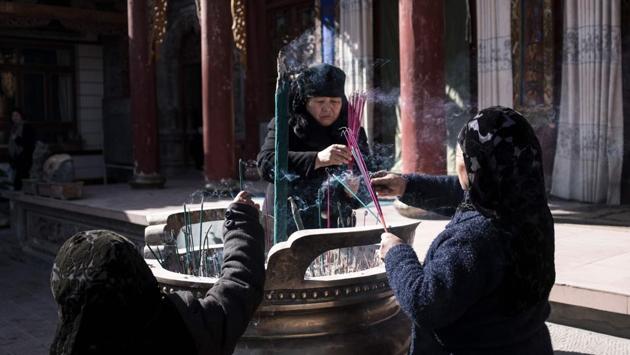 Ethnic Hui Muslim women praying in a courtyard at a religious site in Linxia. Women in headscarves dish out boiled lamb in mirror-panelled halal eateries while streams of white-hatted men meander into mosques for afternoon prayers, passing shops hawking rugs, incense and “eight treasure tea,” a local speciality including dates and dried chrysanthemum buds. (Johannes Eisele / AFP) Ethnic Hui Muslim women praying in a courtyard at a religious site in Linxia. Women in headscarves dish out boiled lamb in mirror-panelled halal eateries while streams of white-hatted men meander into mosques for afternoon prayers, passing shops hawking rugs, incense and “eight treasure tea,” a local speciality including dates and dried chrysanthemum buds. (Johannes Eisele / AFP)