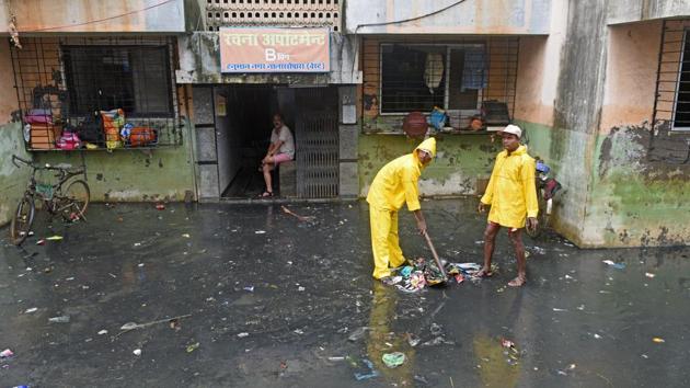 Municipal workers clear garbage as water breaches houses in Hanuman Nagar, Nallasopara. Sulakshana Mahajan, senior urban planner, said that drainage channels that take water down to the sea get blocked by excessive construction and civic authorities do not clear them. She pointed out, that in development plans, such channels are generally not marked, or topography is not considered, which becomes a major issue. (Satyabrata Tripathy / HT Photo)