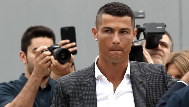 Portuguese footballer Cristiano Ronaldo surrounded by photographs looks on as he greets supporters outside the Juventus medical center at the Alliance stadium in Turin on July 16, 2018. Cristiano Ronaldo arrived in Turin ahead of his official unveiling as Juventus' superstar summer signing on July 17. (AFP) Portuguese footballer Cristiano Ronaldo surrounded by photographs looks on as he greets supporters outside the Juventus medical center at the Alliance stadium in Turin on July 16, 2018. Cristiano Ronaldo arrived in Turin ahead of his official unveiling as Juventus' superstar summer signing on July 17. (AFP)