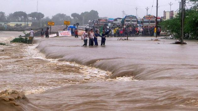 People make way through flood waters on the Una-Veraval highway after heavy rains, in Una town of Gir Somnath district in Gujarat. (PTI) People make way through flood waters on the Una-Veraval highway after heavy rains, in Una town of Gir Somnath district in Gujarat. (PTI)