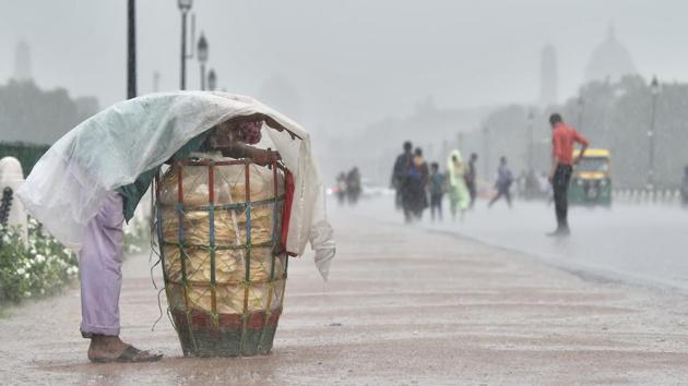 A vendor covers himself with a plastic sheet during heavy rain at Rajpath, in New Delhi, on Monday, July 16, 2018.(Ajay Aggarwal/HT PHOTO)