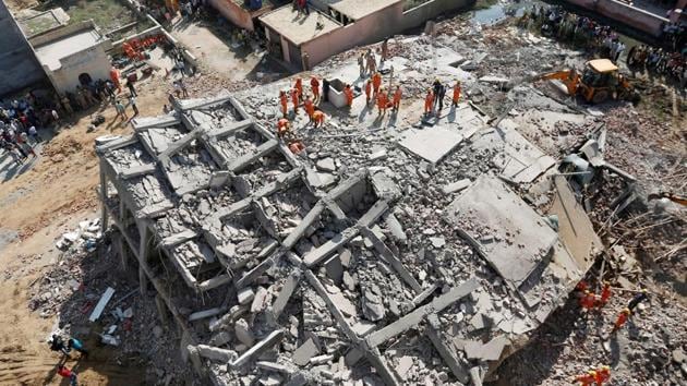 Rescue workers look for survivors amidst the rubble at the site of a collapsed residential building at Shah Beri village in Greater Noida.(REUTERS)