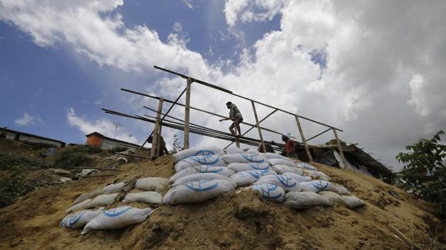 A man builds a new shelter for Mustawkima, whose former shelter was destroyed by heavy rains in Balukhali refugee camp. She sold off her donated rations of rice, lentils and oil so she could hire men to build a sturdier shelter atop a hill. The bamboo and sandbags were donated by aid agencies. Though living here could spell doom in the monsoon, she will anyway. (Wong Maye-E / AP) A man builds a new shelter for Mustawkima, whose former shelter was destroyed by heavy rains in Balukhali refugee camp. She sold off her donated rations of rice, lentils and oil so she could hire men to build a sturdier shelter atop a hill. The bamboo and sandbags were donated by aid agencies. Though living here could spell doom in the monsoon, she will anyway. (Wong Maye-E / AP)