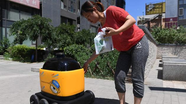 A woman picks up groceries delivered by a Zhen Robotics delivery robot. Equipped with a GPS system, cameras and radar, the robots are seen by their creator as the future of logistics in China. To get a delivery via the “little yellow horse”, the customer selects the desired products, taps in the address and pays via their phone. (Greg Baker / AFP) A woman picks up groceries delivered by a Zhen Robotics delivery robot. Equipped with a GPS system, cameras and radar, the robots are seen by their creator as the future of logistics in China. To get a delivery via the “little yellow horse”, the customer selects the desired products, taps in the address and pays via their phone. (Greg Baker / AFP)