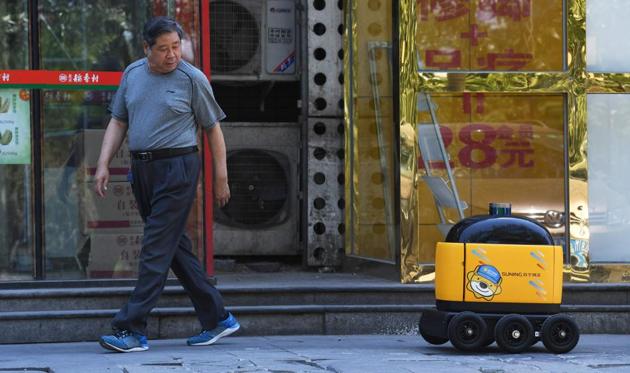 Along a quiet residential street on the outer edges of Beijing, a yellow and black cube about the size of a small washing machine trundles leisurely to its destination. This “little yellow horse” is an autonomous delivery robot, ferrying daily essentials like drinks, fruit and snacks from the local store to the residents of the “Kafka” compound in the Chinese capital. (Greg Baker / AFP) Along a quiet residential street on the outer edges of Beijing, a yellow and black cube about the size of a small washing machine trundles leisurely to its destination. This “little yellow horse” is an autonomous delivery robot, ferrying daily essentials like drinks, fruit and snacks from the local store to the residents of the “Kafka” compound in the Chinese capital. (Greg Baker / AFP)