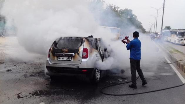A man douses a fire in an SUV in Gurugram, Haryana on July 18, 2018. (Yogesh Kumar/ HT Photo)