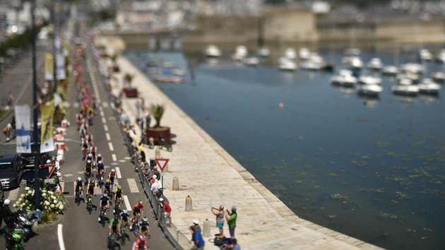 A photo taken with a tilt and shift lens shows the pack riding along the harbour of Concarneau during the fifth stage of the cycling race between Lorient and Quimper on July 11, 2018. (Marco Bertorello / AFP) A photo taken with a tilt and shift lens shows the pack riding along the harbour of Concarneau during the fifth stage of the cycling race between Lorient and Quimper on July 11, 2018. (Marco Bertorello / AFP)