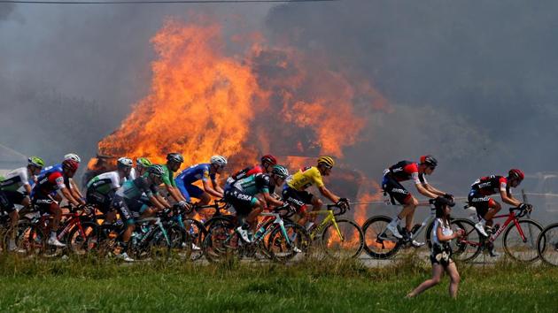 The peloton passes hay bales on fire during the stage 6 Brest to Mur-de-Bretagne Guerleden on July 12, 2018. (Stephane Mahe / REUTERS) The peloton passes hay bales on fire during the stage 6 Brest to Mur-de-Bretagne Guerleden on July 12, 2018. (Stephane Mahe / REUTERS)