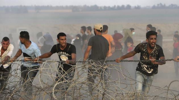 Protesters try to move part of the fence of the Gaza Strip border with Israel, during a protest east of Khan Younis, southern Gaza on Friday. Israel targeted Hamas positions in Gaza, killing four Palestinians on Friday in a series of air strikes after gunmen shot at soldiers near the border, officials said.(AP Photo)