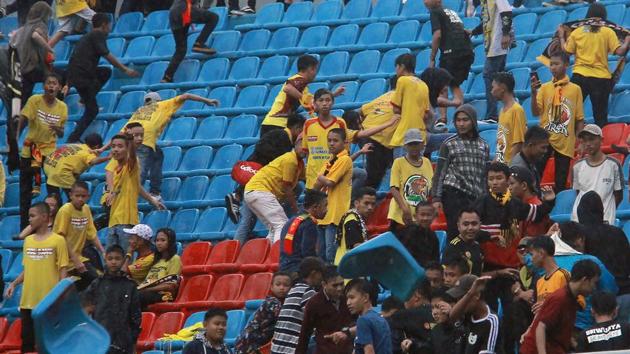 Spectators throwing chairs ripped from the stands during the league football match between Sriwijaya FC and Arema FC.(AFP)
