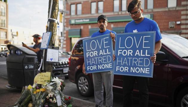 People hold signs at a memorial remembering the victims of Sunday's shooting in Toronto on Monday, July 23, 2018. (AP)