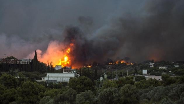 Flames rise as a wildfire burns in the town of Rafina, near Athens, on July 23, 2018. (AFP) Flames rise as a wildfire burns in the town of Rafina, near Athens, on July 23, 2018. (AFP)
