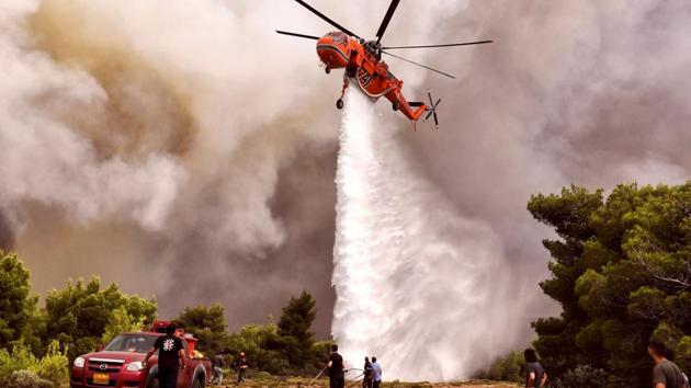 A firefighting helicopter drops water to extinguish flames in Kineta. The European Union activated its Civil Protection Mechanism after Greece sought help. Several countries said they were sending aircraft to help fight the flames. More than 280 firefighters were still at work in the northeast of Athens, while another 200 firefighters were tackling the second forest fire in the west of Athens. (Angelos Tzortzinis / AFP) A firefighting helicopter drops water to extinguish flames in Kineta. The European Union activated its Civil Protection Mechanism after Greece sought help. Several countries said they were sending aircraft to help fight the flames. More than 280 firefighters were still at work in the northeast of Athens, while another 200 firefighters were tackling the second forest fire in the west of Athens. (Angelos Tzortzinis / AFP)