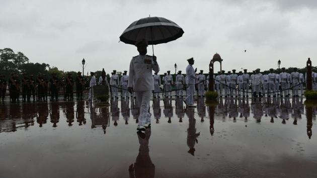 Navy contingents are seen standing as it rains on the occasion of Kargil Vijay Diwas at India Gate. While the cloudy sky had lowered the day temperature to 32.2 degrees Celsius the previous day (two degrees below normal), weather officials have forecast that the maximum temperature could drop further to around 31 degrees by Thursday. (Arvind Yadav / HT Photo)