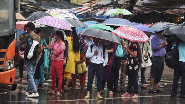People wait for transport during morning office hours amid heavy rains. Several parts of Ghaziabad were also waterlogged, besides a road caved in Vasundhara area. (Raj K Raj / HT Photo)