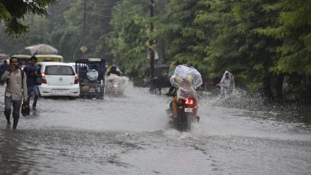 Commuters wade through a flooded street at Noida’s Sector 12. While Safdarjung received 4.6 mm of rainfall until 8.30 am, Palam recorded around 9.3 mm. Meteorological department officials have forecast that precipitation may also occur intermittently on Friday because two rain-triggering systems – cyclonic circulation and low pressure – have developed over the region. (Mohd Zakir / HT Photo)