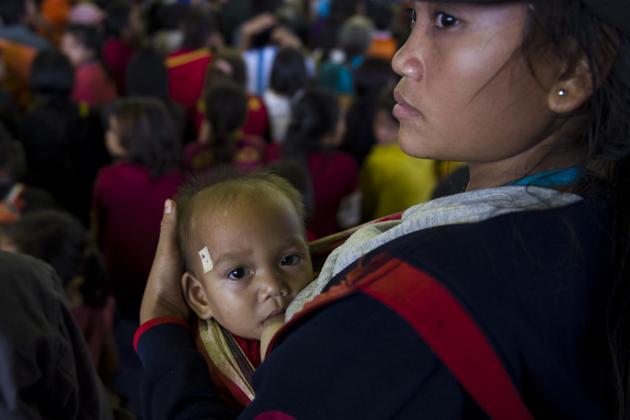 A woman with her child seek shelter with other displaced residents in Paksong town. Vietnam also came forward and dispatched military and medical personnel to support rescue efforts and Thailand said it was sending close to $150,000 in aid. (Ye Aung Thu / AFP) 