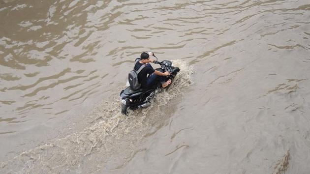 A rider crosses a waterlogged street near Mayur Vihar. “A well-marked low pressure area, which was located over Jharkhand earlier this week, has shifted towards the northwest part of the country. Besides this, a cyclonic circulation has also developed over Madhya Pradesh and Uttar Pradesh. These two systems have come together to trigger the rain,” said BP Yadav, deputy director general of the India Meteorological Department. (Ajay Aggarwal / HT Photo) 