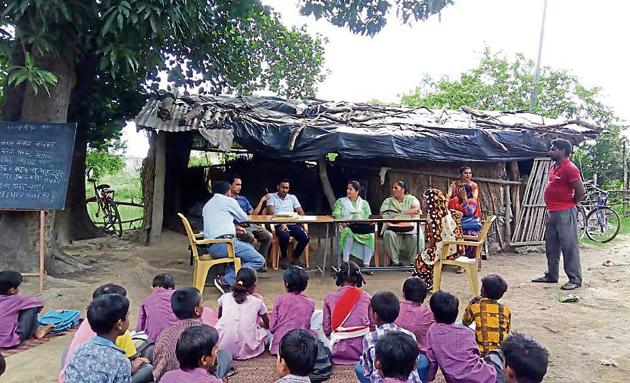 Education department officials meet villagers as students of a primary school study in the open at Pipal Hattha village in US Nagar district of Uttarakhand. (HT Photo) Education department officials meet villagers as students of a primary school study in the open at Pipal Hattha village in US Nagar district of Uttarakhand. (HT Photo)