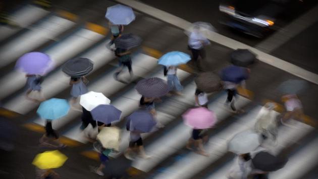 Pedestrians carry umbrellas as they walk in a crosswalk in Beijing on July 24, 2018. (Mark Schiefelbein / AP) Pedestrians carry umbrellas as they walk in a crosswalk in Beijing on July 24, 2018. (Mark Schiefelbein / AP)