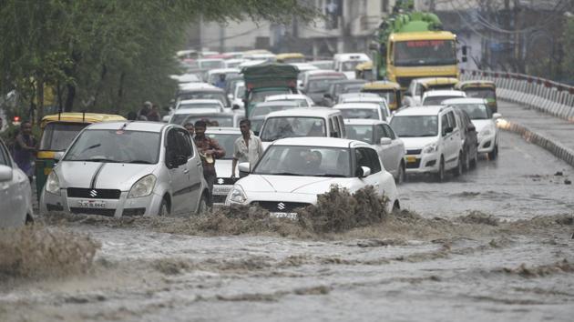 Traffic moves at a slow pace as vehicles cross a water logged street after heavy rains lashed the capital on Thursday.(Sanchit Khanna/HT Photo)