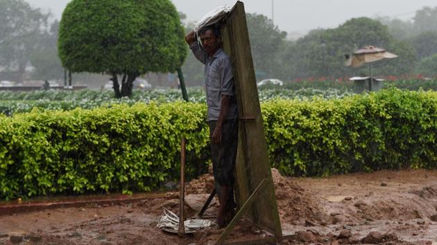 A worker stands on a roadside as he protects himself from heavy rain in New Delhi on July 26, 2018. (Money Sharma / AFP) A worker stands on a roadside as he protects himself from heavy rain in New Delhi on July 26, 2018. (Money Sharma / AFP)