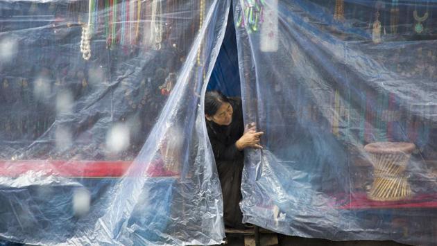 An exile Tibetan looks through plastic sheets draped over her roadside stall selling trinkets during rainfall in Dharmsala, Himachal Pradesh on July 21, 2018. (Ashwini Bhatia / AP) An exile Tibetan looks through plastic sheets draped over her roadside stall selling trinkets during rainfall in Dharmsala, Himachal Pradesh on July 21, 2018. (Ashwini Bhatia / AP)