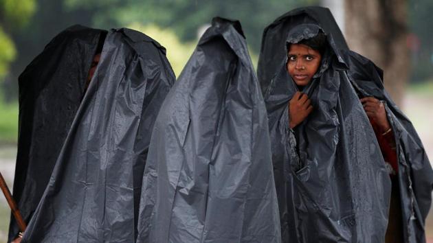 Women cover themselves with plastic sheets as it rains in New Delhi, on July 26, 2018. (Adnan Abidi / REUTERS) Women cover themselves with plastic sheets as it rains in New Delhi, on July 26, 2018. (Adnan Abidi / REUTERS)
