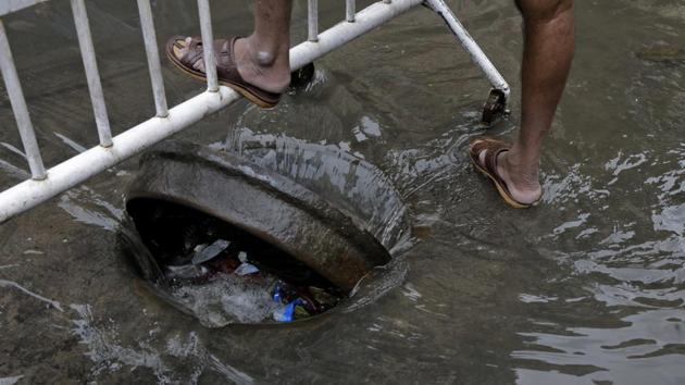 A civic worker, stands guard after opening a man-hole to drain water quickly in a water logged street following heavy monsoon rain in Kolkata, West Bengal. A civic worker, stands guard after opening a man-hole to drain water quickly in a water logged street following heavy monsoon rain in Kolkata, West Bengal.