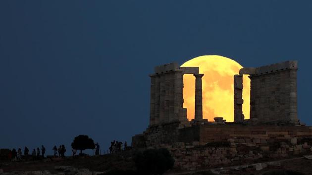 People watch a full moon rising behind the Temple of Poseidon before the eclipse in Cape Sounion, near Athens, Greece. Unlike with a solar eclipse, viewers did not need protective eye gear to observe the rare display. (Alkis Konstantinidis / REUTERS)
