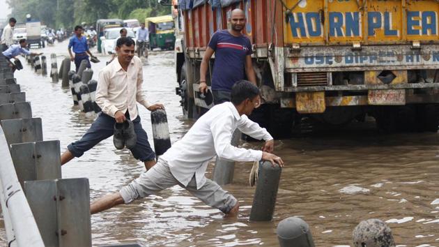 People try to make their way through a waterlogged road after heavy rains, at NH-48, near Sunbeam Company, in Gurugram. In Haryana, Rohtak, Sonipat, Narnaul, Panchkula, Ambala, Yamunanagar, Kurukshetra and parts of the NCR including Gurugram and Faridabad, recorded a fall in temperatures due to the rains. (Yogendra Kumar / HT Photo) People try to make their way through a waterlogged road after heavy rains, at NH-48, near Sunbeam Company, in Gurugram. In Haryana, Rohtak, Sonipat, Narnaul, Panchkula, Ambala, Yamunanagar, Kurukshetra and parts of the NCR including Gurugram and Faridabad, recorded a fall in temperatures due to the rains. (Yogendra Kumar / HT Photo)