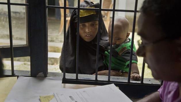 A woman holding her child checks if their names are included in the National Register of Citizens at a draft center. The Assam government started the process of updating the NRC in December 2013. All residents in the state were asked to produce documents proving that they or their families had lived in India before March 24, 1971. (Anupam Nath / AP)