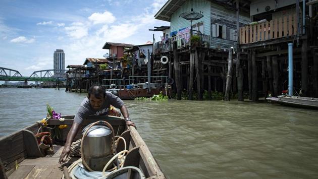 Bhoomin leaves his house in a boat with his home-made metal scuba helmet. “We look for old coins, sometimes we are hired to find lost objects in the river,” said the veteran diver who has been scouring the river for 30 years. Sometimes the find is more macabre -- the divers have stumbled across skulls and skeletons as they feel their way along the river bed in total darkness. (Sippachai Kunnuwong / AFP)