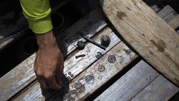 A diver displays rare coins recovered from the bottom of Bangkok's Chao Phraya river. After 15 minutes underwater, the divers resurface with a cotton bag stuffed with mud. Bhoomin pans it out on a metal dish, revealing several 200-year-old copper and bullet coins with pictures of 19th century Thai kings Rama IV and V on them -- artifacts divers call “regulars.” (Sippachai Kunnuwong / AFP)