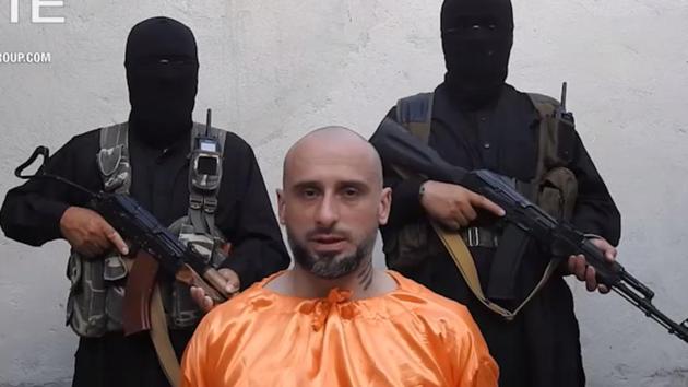 This video image released on July 31, 2018, and provided courtesy of SITE Intelligence Group shows Italian national, Alessandro Sandrini, appealing for his release as two armed men stand behind him in Syria.(AFP Photo)