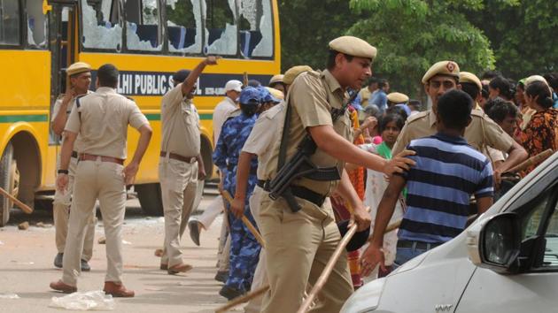 Police and public stand near a school bus that was attacked by a mob after it hit a couple riding a bicycle, in Gurugram on Thursday. Both the husband and wife were killed in the accident. (Parveen Kumar / HT Photo)