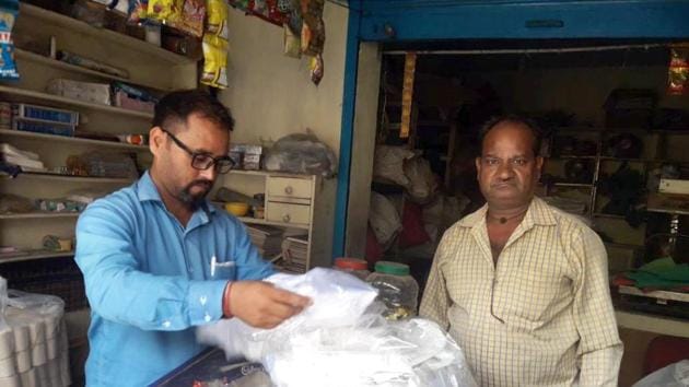 Member of anti-polythene squad issues challan to a shopkeeper for keeping polythene bags in Dehradun.(HT Photo)