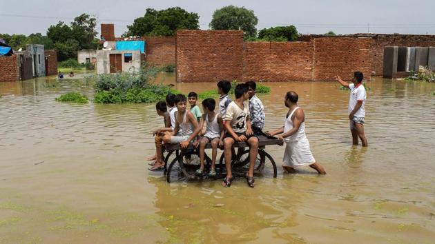 Children ride a cart as they move through a flooded colony, inundated by the Yamuna river, in Mathura on Thursday. (PTI)