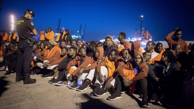A group of migrants sits in front of Spanish Police officers at the port of Algeciras, after being rescued. The European Commission has said that it is willing to increase funding to Spain and Morocco to help manage a rise in migration across the western Mediterranean, though the budget is limited. (Marcos Moreno / AP)