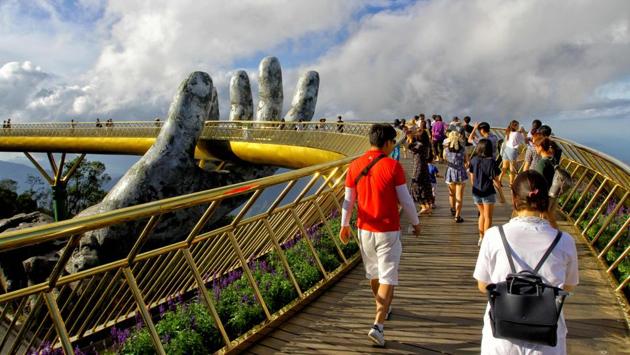 Visitors walk along the 150-meter long Cau Vang ‘Golden Bridge’ in the Ba Na Hills near Danang. Nestled in the forested hills of central Vietnam two giant concrete hands emerge from the trees, holding up a glimmering golden bridge crowded with gleeful visitors taking selfies at the country's latest eccentric tourist draw. (Linh Pham / AFP) Visitors walk along the 150-meter long Cau Vang ‘Golden Bridge’ in the Ba Na Hills near Danang. Nestled in the forested hills of central Vietnam two giant concrete hands emerge from the trees, holding up a glimmering golden bridge crowded with gleeful visitors taking selfies at the country's latest eccentric tourist draw. (Linh Pham / AFP)
